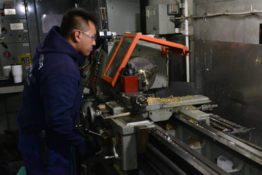 Ein Meereswissenschaftler an Bord des Polarsterns der Küstenwache Cutter Polar Star fertigt mit einer Drehmaschine eine Messingbuchse für die Antriebsmaschinen des Schiffes (Foto: US-Küstenwache von Nick Ameen)