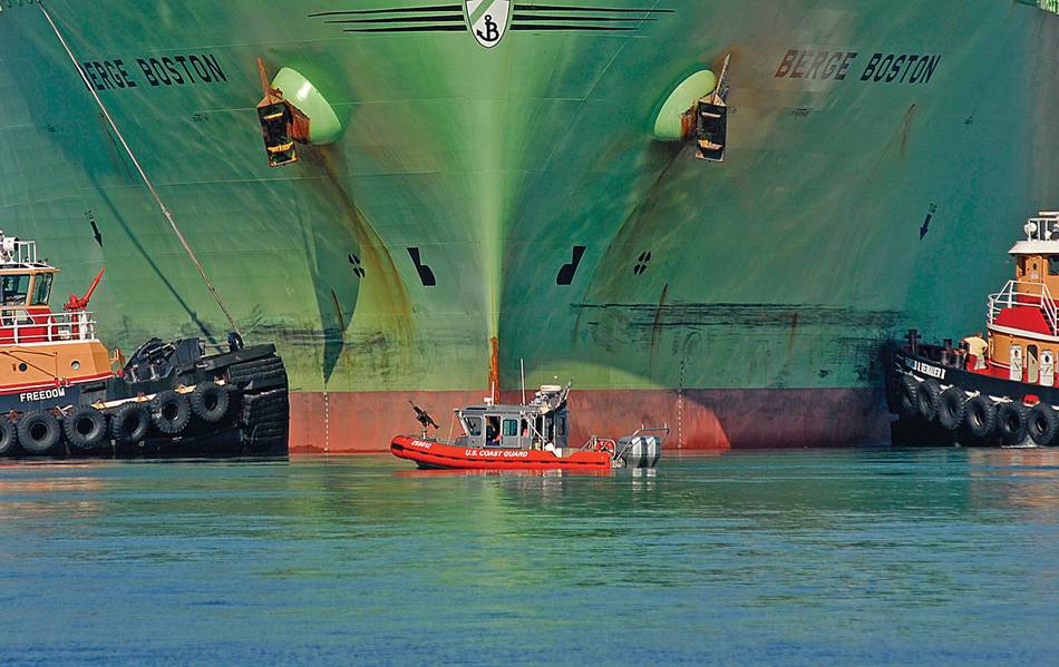 Ein 25 Meter langes Küstenwache-Boot der Coast Guard wird von zwei Schleppern flankiert, während der Flüssigerdgastanker Berge Boston hier an einer LNG-Anlage am Pier festgemacht wird. USCG-Foto von PA2 Luke Pinneo