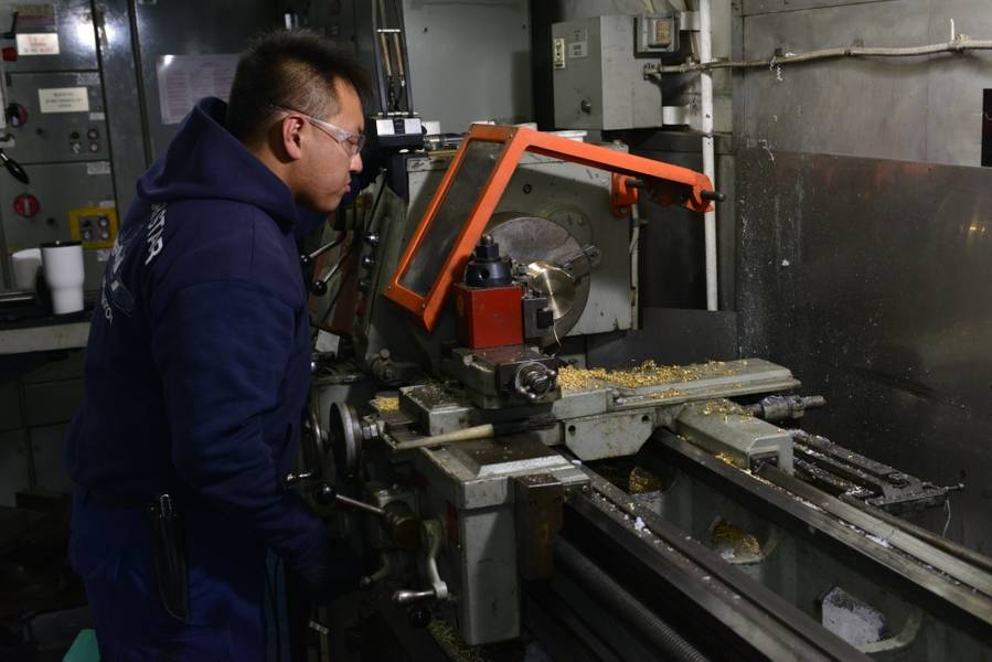 Un técnico en ciencias marinas a bordo del Coast Guard Cutter Polar Star utiliza un torno para fabricar un casquillo de latón para la maquinaria de propulsión del barco (foto de la Guardia Costera de los EE. UU. Por Nick Ameen)
