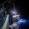 Crew members aboard a NOAA ship in 2016 use a crane to hoist a remotely operated vehicle (ROV) from the water at night. NOAA is seeking proposals for new ocean survey ships that can deploy a variety of equipment, including ROVs like the one pictured here. Credit: NOAA