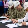 (Left to right) Cmdr. Robby Trotter, Cmdr. Scott Williams and Donny Dorsey sign the delivery document officially handing ownership of the destroyer Paul Ignatius (DDG 17) from Ingalls Shipbuilding to the U.S. Navy. Trotter is the ship’s prospective commanding officer; Williams is the DDG 51 program management representative for Supervisor of Shipbuilding, Gulf Coast; and Dorsey is Ingalls’ DDG 117 ship program manager. Photo by Derek Fountain/HII
