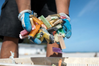 A marine debris team member gathers a handful of disposable cigarette lighters picked up at a beach cleanup site. (NOAA)