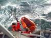Coast Guard crewmembers use a boat hook to pull in a empty life raft after rescuing a man who abandoned his sinking sailing vessel ( U.S. Coast Guard photo by Seaman Alyssa Petty)