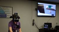 Computer Engineer Daniel Stith shows how to use the hands-free headset for the virtual reality simulation. (Photo: U.S. Navy)