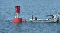 Divers prepare to go underwater for the fastening of the mooring line to its anchor (Photo courtesy of the U.S. Coast Guard)