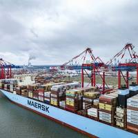 A Maersk boxship alongside in port, working cargo. (c) Maersk