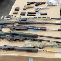 A photo introduced as evidence in the detention hearing for Nihad Al Jaberi includes nine firearms from a shipment interdicted in the Port of Savannah and reassembled, along with other firearms removed during a search of the defendant’s residence. (Photo: U.S. Department of Justice)