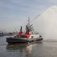 A tug spray from the Port of Durban’s new UMBILO tug while the Port of Richards Bay’s Usiba tug is lowered into the water in the background. (Photo: TNPA)