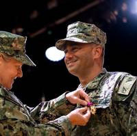 Adm. Linda Fagan, commandant, U.S. Coast Guard, presents an award for service to Capt. Benjamin Berg, commander, Patrol Forces Southwest Asia (PATFORSWA) aboard Naval Support Activity Bahrain, June 16, 2022, during a change of command ceremony. As the commander of the most extensive Coast Guard base outside of the United States, Berg served as the senior U.S. Coast Guard representative in the U.S. Central Command (CENTCOM) area of responsibility, providing support to maritime security operations