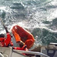 Coast Guard crewmembers use a boat hook to pull in a empty life raft after rescuing a man who abandoned his sinking sailing vessel ( U.S. Coast Guard photo by Seaman Alyssa Petty)