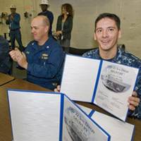 Doug Lounsberry (left) and Cmdr. Joe Tuite (center) applaud as Cmdr. Jon Haydel, commanding officer of San Diego (LPD 22), holds up the ceremonial document acknowledging the ship's custody transfer from Huntington Ingalls Industries to the U.S. Navy. Lounsberry is vice president of the LPD 17 Program at Ingalls. (Photo: HII)
