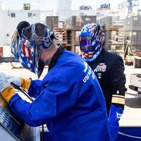 During a keel laying ceremony for the future USS William Charente on Aug. 29, a welder from General Dynamic Bath Iron Works etches the initials of the keel honorees into the keel plate. (Photo: U.S. Navy)