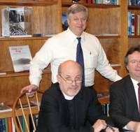 Eric Larsson (standing), Director of Maritime Education, and SCI’s President & Executive Director, the Rev. David M. Rider (L), sign the contract for the first phase of SCI’s Houston simulator upgrades with Kongsberg Maritime, represented by Area Sales Manager Henry Tremblay (R).
