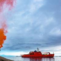 Expeditioners holding up flares to farewell the Aurora Australis, as it departs Mawson research station, February 26, 2020 (Photo: Matt Williams)