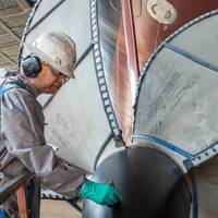 Lindell Toombs, a Newport News shipbuilder with 41 years of experience, applies a protective coating to one of the four propellers on the aircraft carrier Gerald R. Ford (CVN 78). Photo by Chris Oxley