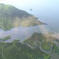 Pictured here is an aerial photo of smoke billowing from a wellhead after a towing vessel's dredge barge allided with the structure in Barataria Bay, La., as the vessel and barge exited Mud Lake, July 27, 2010. The barge was en route to the towing vessel's facility in Berwick Bay when the incident occurred. More than 150 response personnel and 31 boats responded to a mixture of oil and gas emanating from the wellhead. Official U.S. Coast Guard photo