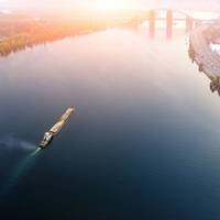 Russia's invasion of Ukraine emphasizes the importance of efficient maritime traffic to national security and the world economy. Pictured is an aerial cityscape of Kiev and river Dnipro at sunset, with a tugboat and barge heading down river Dnieper. Copyright Kirill Gorlov/AdobeStock