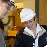 Susan Ford Bales receives a lesson in connecting instrumentation wiring during her Oct. 11 visit to Newport News Shipbuilding. (Photo: Huntington Ingalls Industries)