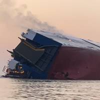 The stern view of the Golden Ray six hours after the heeling event. Flame and smoke emanate from cargo decks on the starboard side of the vessel. (Photo courtesy of the U.S. Coast Guard)