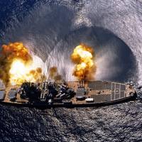 USS Iowa (BB-61) Fires a full broadside of nine 16/50 and six 5/38 guns during a target exercise near Vieques Island, Puerto Rico, 1 July 1984. Photographed by PHAN J. Alan Elliott. Note concussion effects on the water surface, and 16-inch gun barrels in varying degrees of recoil. Official U.S. Navy Photograph, from the the Department of Defense Still Media Collection.