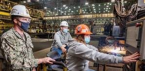 Erika Lynd, Ingalls burner workleaderman, cuts steel into patterns using the Avenger IV plasma cutter, signifying 100 tons of steel cut and start of fabrication for the destroyer Jeremiah Denton (DDG 129). Observing the milestone are U.S. Navy Cmdr. Sean Doherty, DDG program manager’s representative, and Ben Barnett, Ingalls Shipbuilding’s DDG 129 ship program manager. Photo by Derek Fountain/HII