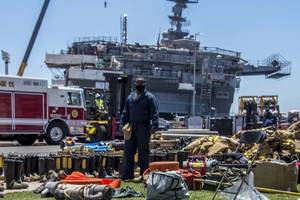 A sailor looks at firefighting gear laid out in front of the amphibious assault ship USS Bonhomme Richard (LHD 6). (U.S. Navy Photo by Natalie M. Byers)