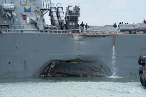 Damage to the portside is visible as the guided-missile destroyer USS John S. McCain (DDG 56) steers towards Changi Naval Base, Republic of Singapore, following a collision with the merchant vessel Alnic MC while underway east of the Straits of Malacca and Singapore. Significant damage to the hull resulted in flooding to nearby compartments, including crew berthing, machinery, and communications rooms. Damage control efforts by the crew halted further flooding. (U.S. Navy photo by Mass Communica