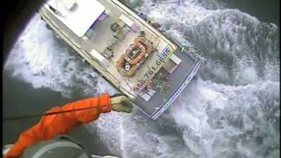 A Coast Guard rescue swimmer is lowered to the Osprey II and a man suffering from chest pains is hoisted back up Saturday near Port Mansfield, Texas. U.S. Coast Guard video by Air Station Corpus Christi.