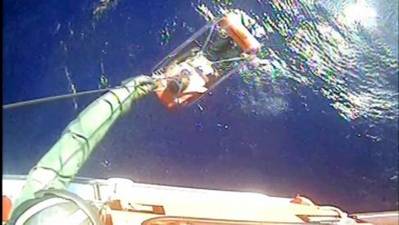 A helicopter rescues one of 12 crewmembers who abandoned ship in Cuban territorial seas December 26. Two USCG helicopter crews responded and subsequently rescued all 12 crewmembers from the sinking 120-foot coastal freighter. (Screenshot from USCG video)