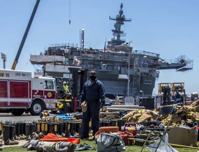 A sailor looks at firefighting gear laid out in front of the amphibious assault ship USS Bonhomme Richard (LHD 6). (U.S. Navy Photo by Natalie M. Byers)