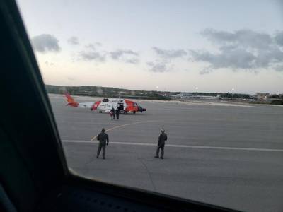 A U.S. Coast Guard helicopter crew walks an ailing mariner to an aircraft in Providenciales, Turks and Caicos, on Wednesday. The man was experiencing health complications aboard the tug Patriarch and needed higher level medical care. (U.S. Coast Guard photo)