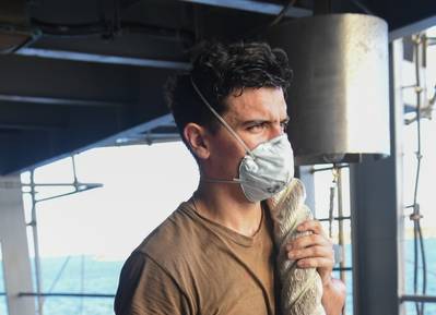 A U.S. Navy Seaman holds onto mooring line on the fantail of the aircraft carrier USS Theodore Roosevelt as the ship departs Apra Harbor May 21, 2020, after being sidelined in Guam due to a COVID-19 outbreak on board. (U.S. Navy photo by Erik Melgar)