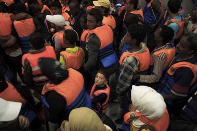  A young boy surrounded by adults after being rescued in June 2014 from a boat on the Mediterranean Sea. Photo: UNHCR/A. D’Amato