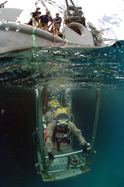 Chief Warrant Officer Guy Inzunza rides a stage to the sea bed during a dive from the Military Sealift Command rescue and salvage ship USNS Grasp.