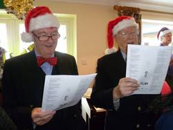 Commander Brian Boxall-Hunt OBE, Chief Executive of the Society and Capt. Braithwaite singing carols.