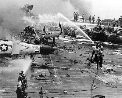 Crew members fight a series of fires and explosions on the carrier USS Forrestal's after flight deck, in the Gulf of Tonkin, 29 July 1967. The conflagration took place as heavily-armed and fueled aircraft were being prepared for combat missions over North Vietnam. (Official U.S. Navy Photograph.)