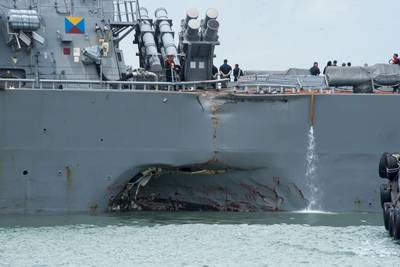 Damage to the portside is visible as the USS John S. McCain steers toward Changi Naval Base, Singapore, following a collision with the merchant vessel Alnic MC while underway east of the Straits of Malacca and Singapore. Significant damage to the hull resulted in flooding to nearby compartments, including crew berthing, machinery and communications rooms. (U.S. Navy photo by Joshua Fulton)