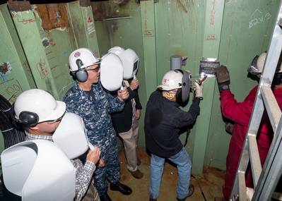 David Bazemore welds a ceremonial plate into the new mast on the aircraft carrier USS Abraham Lincoln (CVN 72). Also pictured (left to right) are Capt. Ronald L. Ravelo, incoming commanding officer, CVN 72; Ken Mahler, Newport News' vice president, Navy Programs; Capt. Karl O. Thomas, outgoing commanding officer, CVN 72; Bruce Easterson, program director, CVN 72 RCOH; and Newport News shipbuilder Leary Putrell. Photo by Chris Oxley/HII