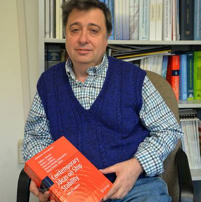 Dr. Vadim Belenky, a naval architect in the Simulations and Analysis Branch at Naval Surface Warfare Center, Carderock Division, holds a copy of Contemporary Ideas on Ship Stability: Risk of Capsizing on Jan. 23, 2019. The book is a compilation of papers from engineers, naval architects and professors from around the world, for which he was the editor in chief. (U.S. Navy photo by Kelley Stirling/Released)