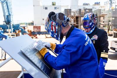 During a keel laying ceremony for the future USS William Charente on Aug. 29, a welder from General Dynamic Bath Iron Works etches the initials of the keel honorees into the keel plate. (Photo: U.S. Navy)