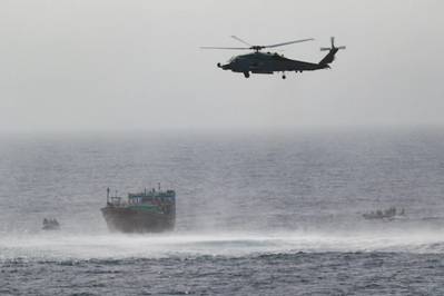 GULF OF OMAN (May 16, 2022) An MH-60R Seahawk from Helicopter Maritime Strike Squadron (HSM) 35, Detachment 1, provides aerial support to an interdiction team from guided-missile destroyer USS Momsen (DDG 92) approaching a fishing vessel May 16. The vessel was seized while transiting international waters in the Gulf of Oman. Photo By: MC3 Lily Gebauer