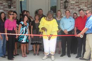 From left to right: Bridget Patterson, Catina Guidry, Candace Landry, Michelle Breaux, Edna D. Lopez, Sarah Schultz, Mona Delcambre, Ed Schultz, Selina Henry (cutting the ribbon), Sara Faulk, Jason Bergeron, Sheila Peckinpaugh, Charlie Hardy, Gerald Faulk