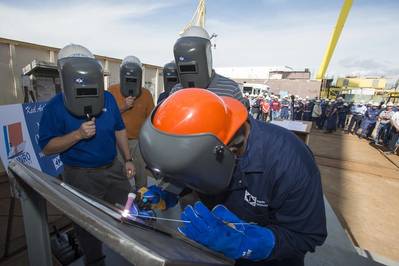 Roderick P. Funches, a structural welder at Ingalls Shipbuilding, welds the initials of Julie Sheehan on a ceremonial keel plate that will be welded to WMSL 755, the National Security Cutter named in honor of her great uncle, Douglas A. Munro. Photo by Andrew Young/HII