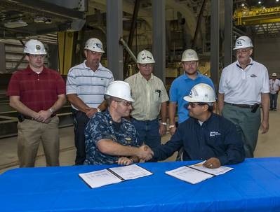 Lt. Cmdr. Stephen Blevins (seated, left) shakes hands with John Fillmore. Blevins is the Navy's DDG 1000 program manager at Supervisor of Shipbuilding Gulf Coast; Fillmore is Ingalls' DDG 1000 program manager for deckhouse and hangar. Standing (left to right) are Jonathan Graves, deputy program manager’s representative, SupShip Gulf Coast; Jeff Roberts, DDG 1000 program management; Neil Adams, general ship superintendent; Dell Simmons, composite superintendent; and Steve Sloan, DDG 1000 program 