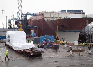 The Rolls-Royce MT30 gas turbine enclosure, shrink wrapped for protection, arrives alongside HMS Queen Elizabeth, prior to installation at Babcock’s Rosyth yard in Scotland.