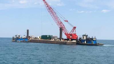 The vessel Kimberly Selvick (left), connected to a crane barge, is pushed by a tug through Lake Michigan after being salvaged from the shores of Lake Michigan near Burnham Park outside of Chicago, May 10, 2014. The Kimberly Selvick became partially submerged after taking on water May 5. (U.S. Coast Guard photo by Lt. Heidi Braglone)