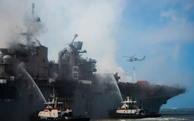 A helicopter provides aerial firefighting support alongside sailors and civilian fire crews on the ground to fight the fire aboard amphibious assault ship USS Bonhomme Richard (LHD 6). (U.S. Navy photo by Mar'Queon A. D. Tramble)