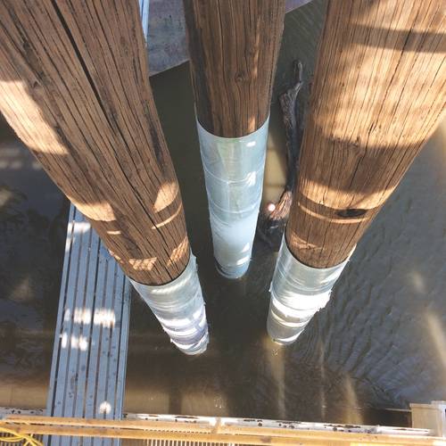 A new engineered repair system for seawalls is based on fiber reinforced polymer (FRP) technology that has been used for several years to repair and strengthen worn and damaged marine piles made of timber or concrete using specialized composites. Pictured here are worn bridge piles being wrapped with FRP laminates in St. Louis