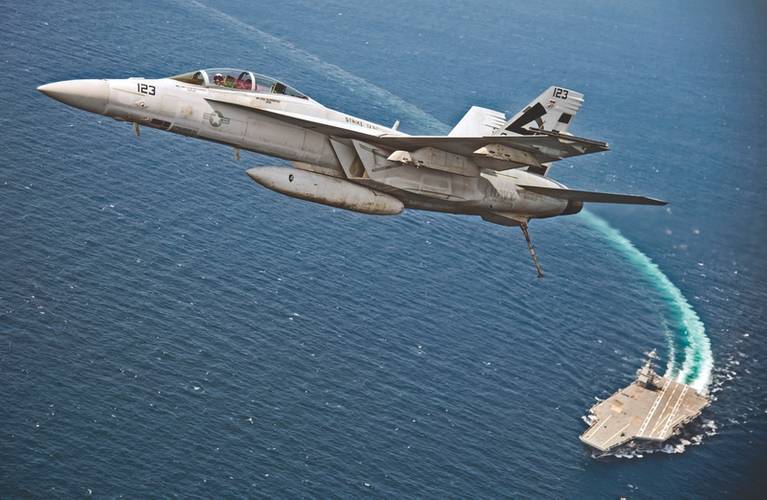 An F/A-18F Super Hornet assigned to Air Test and Evaluation Squadron (VX) 23 flies over USS Gerald R. Ford (CVN 78). The aircraft carrier is underway conducting test and evaluation operations. (U.S. Navy photo by Erik Hildebrandt)