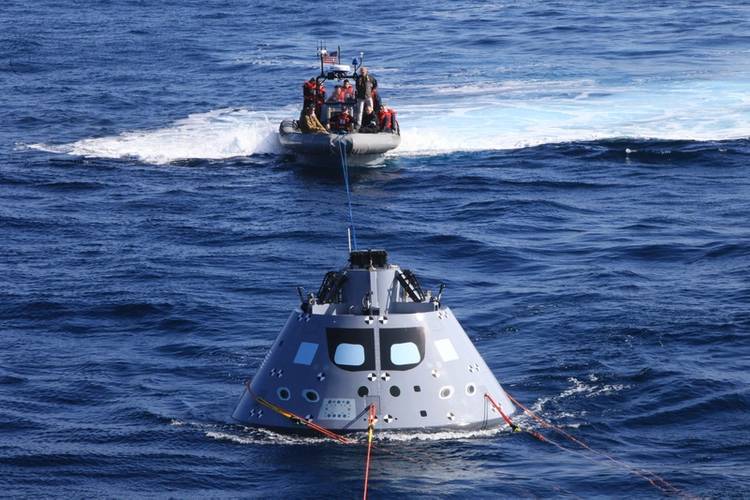 Boats carrying Navy divers and NASA's recovery team guide the capsule to the USS Anchorage as the ship safely operates on station (Photo: NASA)